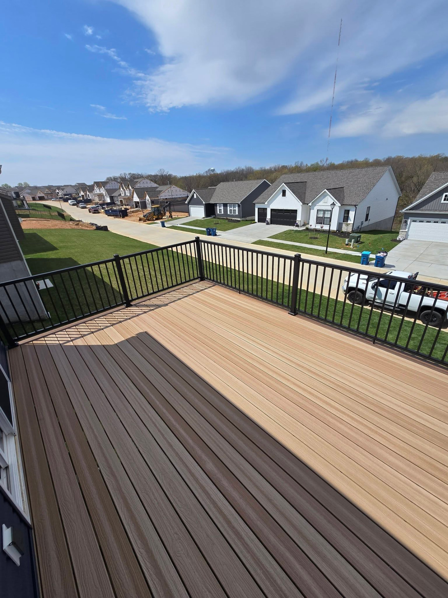 Brand-new deck on a new-construction home — maintenance-free boards with black aluminum handrails overlooking the subdivision by B&R Construction