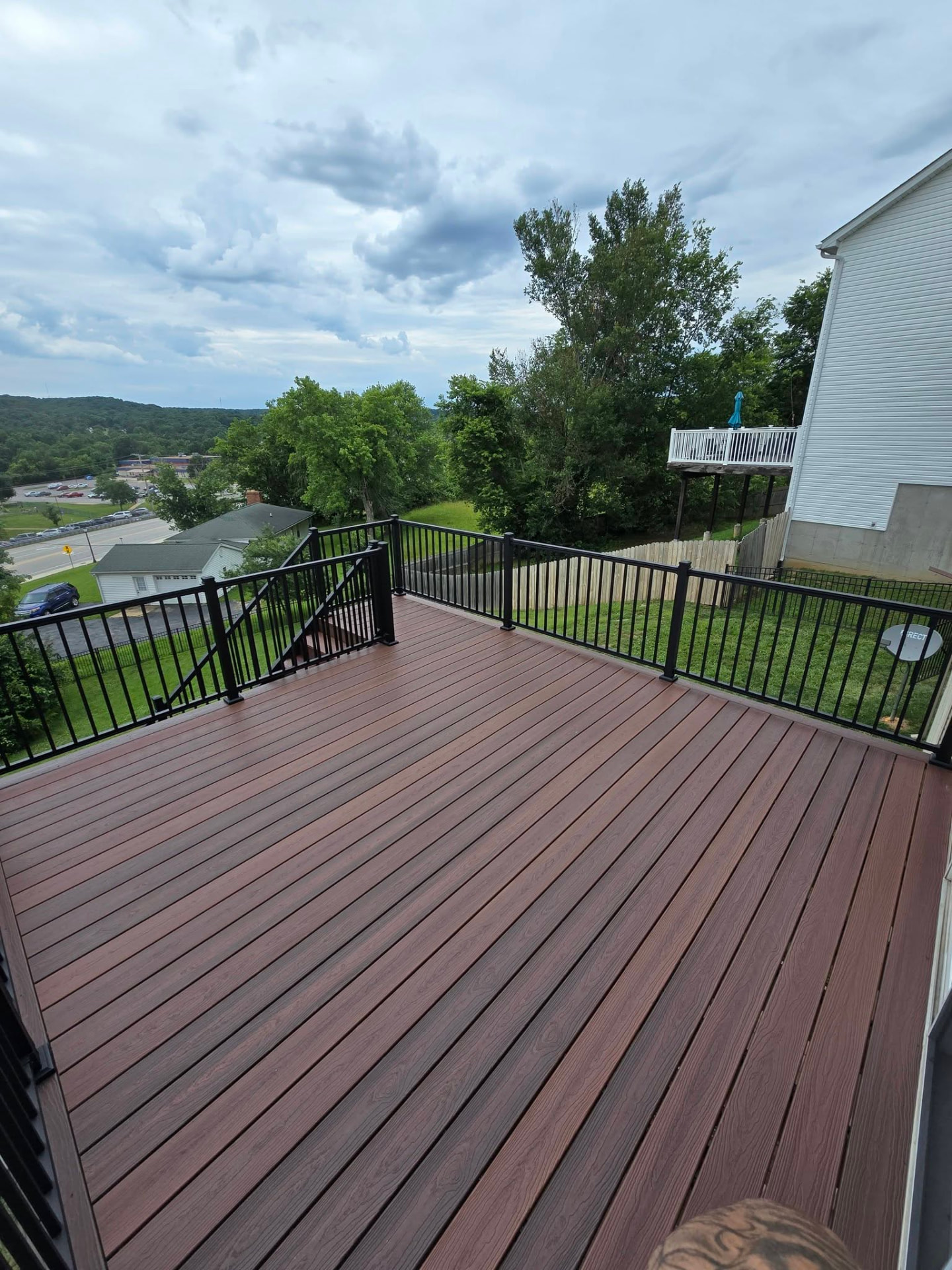 Second-story composite deck with black aluminum handrails overlooking the valley by B&R Construction