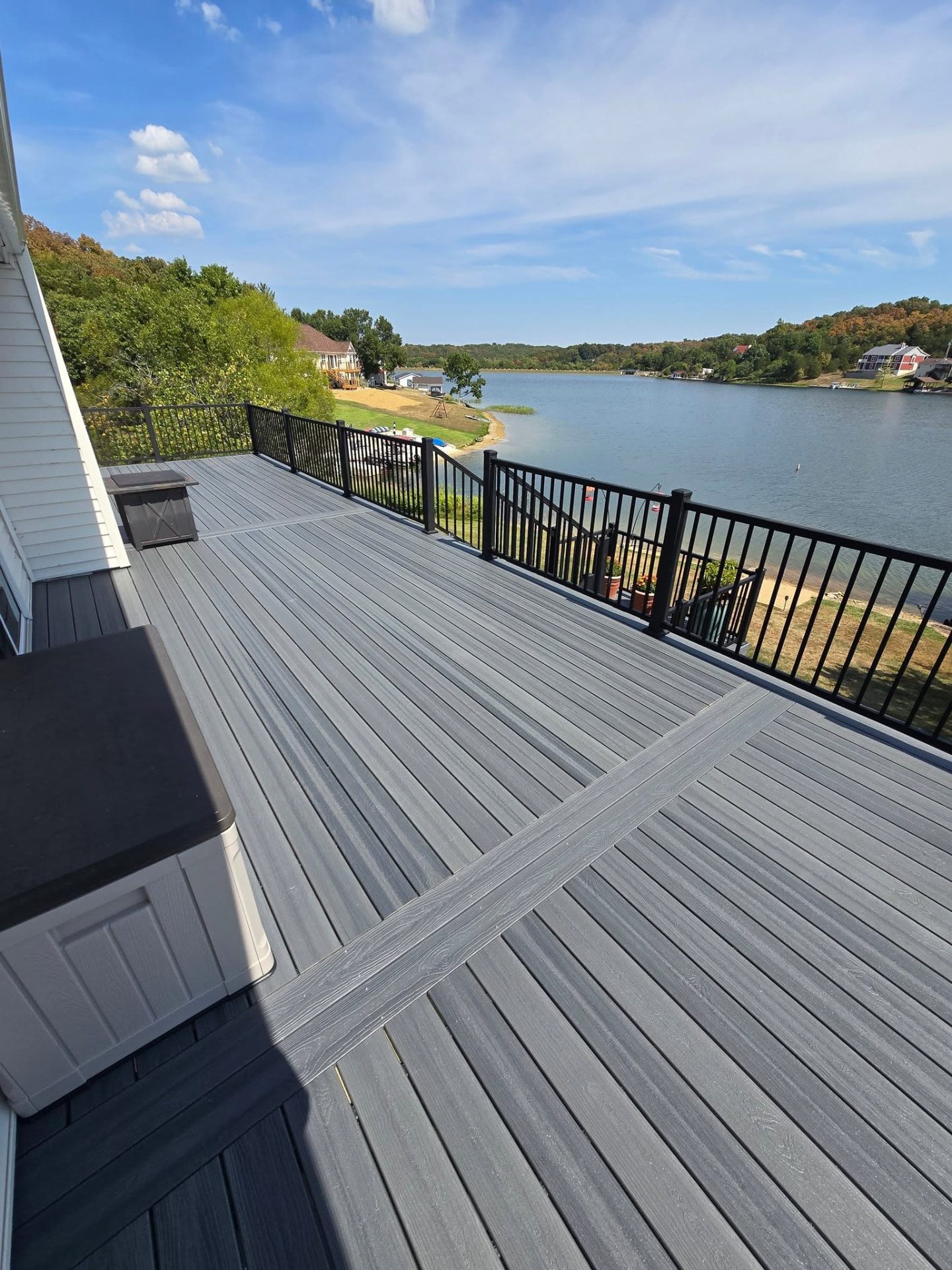50' × 12' Graywood composite deck with picture-frame border and black aluminum handrails, overlooking the lake by B&R Construction